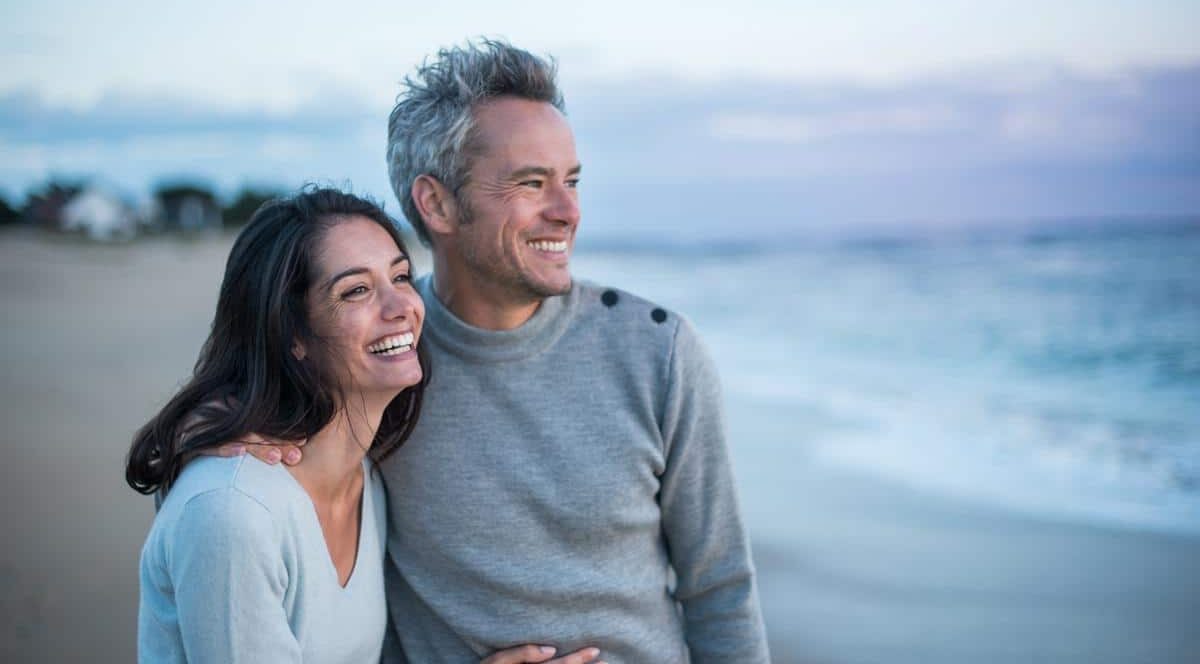 Couple with healthy teeth smiling on beach