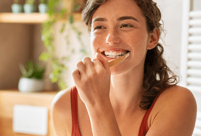 Woman smiling and brushing her teeth, representing health-centered dentistry