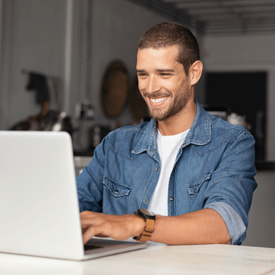 Young man in blue jean shirt, working on a laptop computer, representing new website