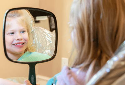 Child looking in dental mirror, representing benefits of family dentistry for kids