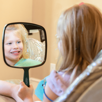 Child looking in dental mirror, representing benefits of family dentistry for kids