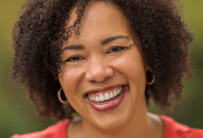 Older woman smiling, representing the debate between dental implants vs bridges